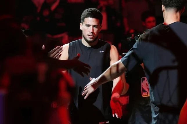 Devin Booker pruža ruku u znak pozdrava, obučeni u crnu majicu bez rukava