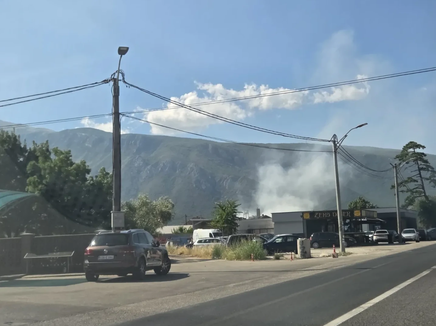 Dim iznad naseljenog mjesta sa planinom u pozadini