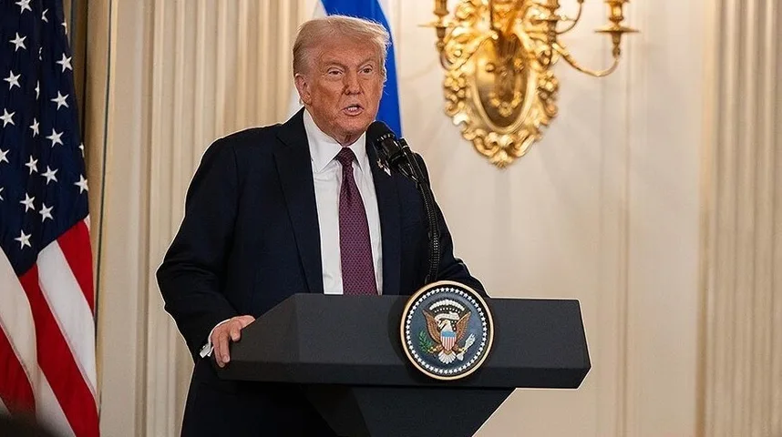 Donald Trump govori sa postolja, s američkom zastavom pored.