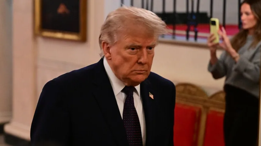 Donald Trump sa ozbiljnim izrazom lica, obučen u tamno odijelo i tamnu kravatu.