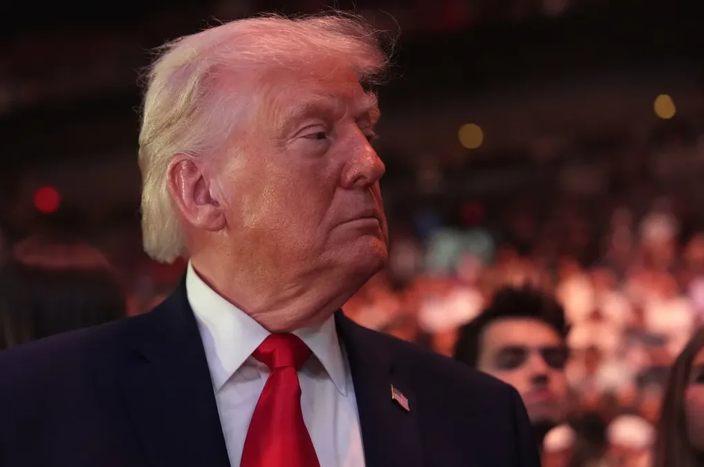 Donald Trump u tamnom odijelu i jarkocrvenoj kravati gleda udesno.