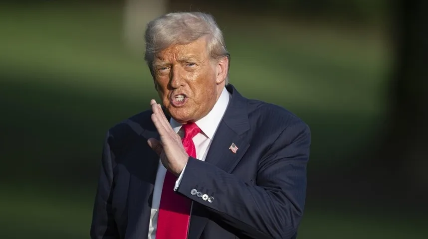 Donald Trump u tamnom odijelu sa bijelom košuljom i crvenom kravatom, gestikulira rukom.