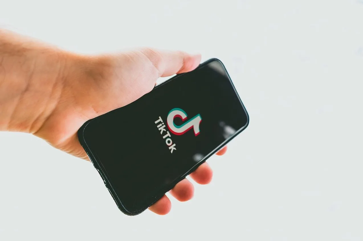 Ruka drži pametni telefon s uključenom aplikacijom TikTok.