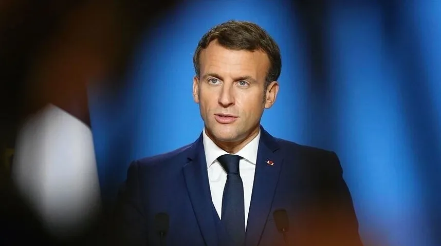 Francuski predsjednik Emmanuel Macron u tamnoplavom odijelu i tamnoj kravati, sa bijelom košuljom, govori pred plavom pozadinom.