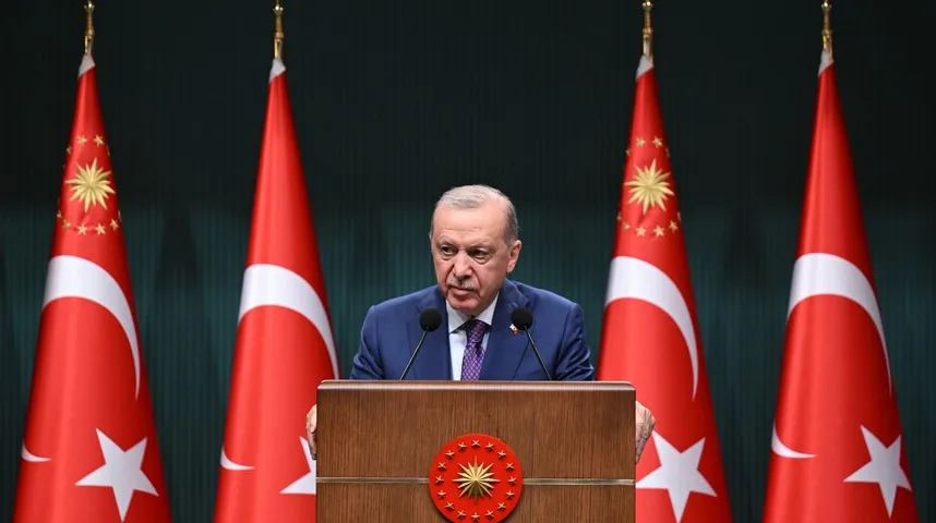 Recep Tayyip Erdoğan govori iza drvene govornice sa turskom zastavom u pozadini.