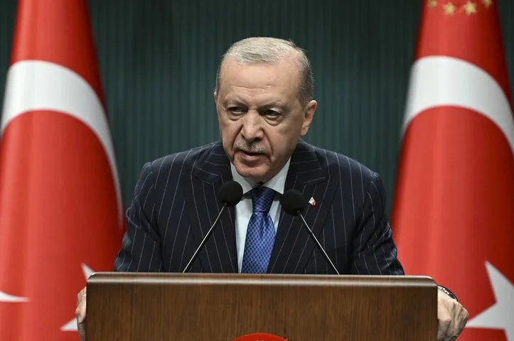 Recep Tayyip Erdogan govori za govornicom, s turskim zastavama u pozadini.