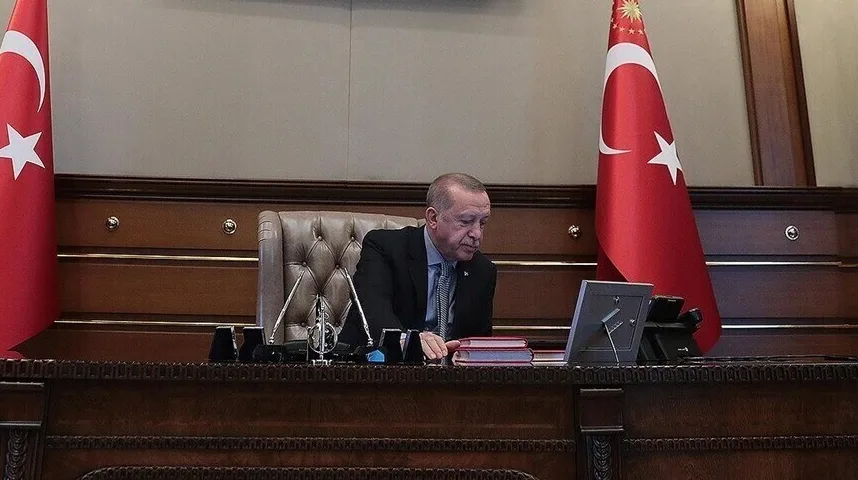 Recep Tayyip Erdogan sjedi za stolom u svom kabinetu pored turske zastave.