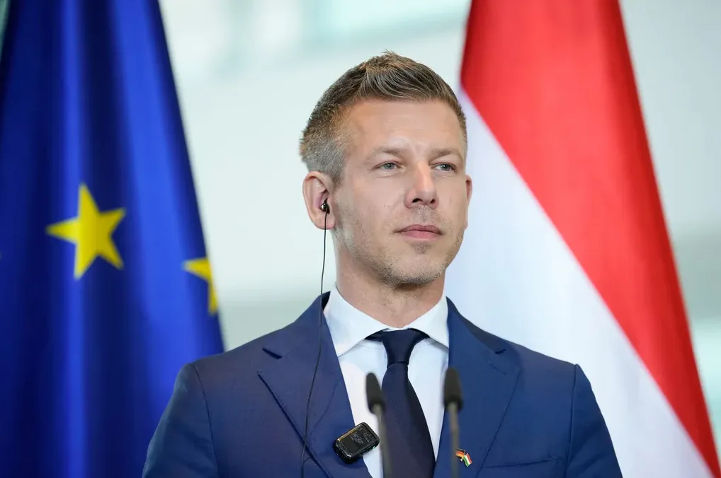 Muškarac u tamnom odijelu sa crnom kravatom ispred zastave Evropske unije i zastave Mađarske.