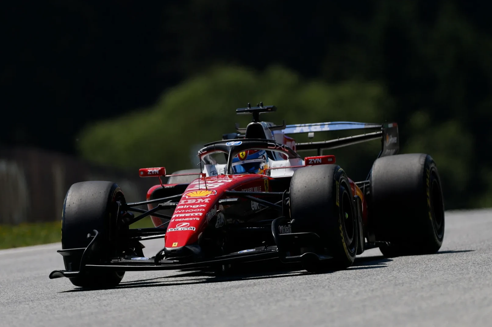 Crveni bolid Formule 1 tima Ferrari u pokretu na trkačkoj stazi.