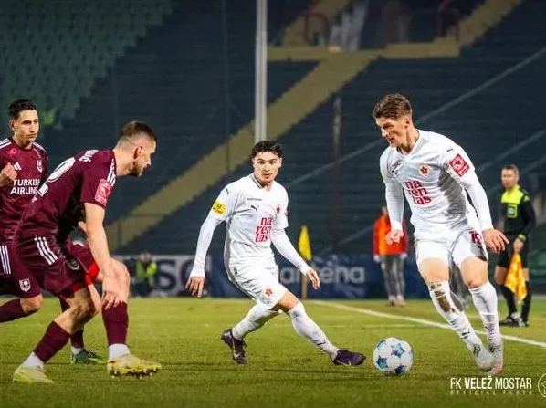Fudbaleri FK Velež Mostar u bijelim dresovima u borbi za loptu na zelenom terenu stadiona