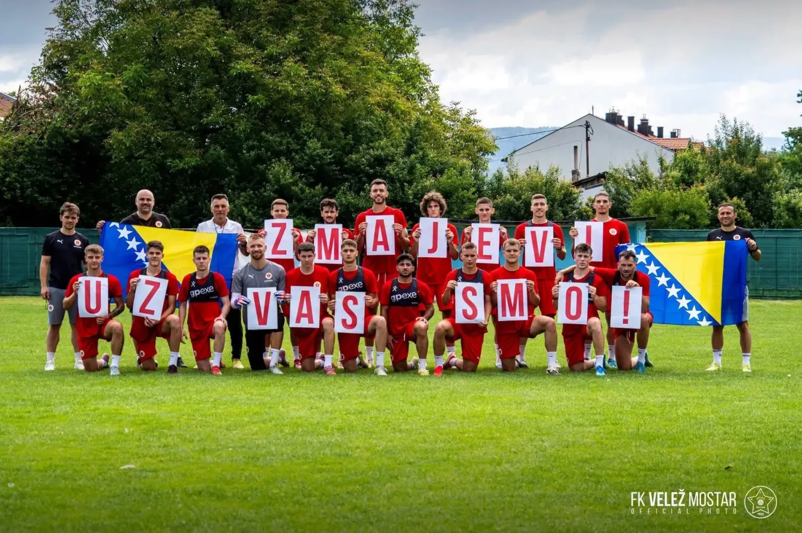 Fudbalska ekipa FK Velež Mostar pozira sa zastavom Bosne i Hercegovine i velikim slovima koja ispisuju "Uz Velež smo".