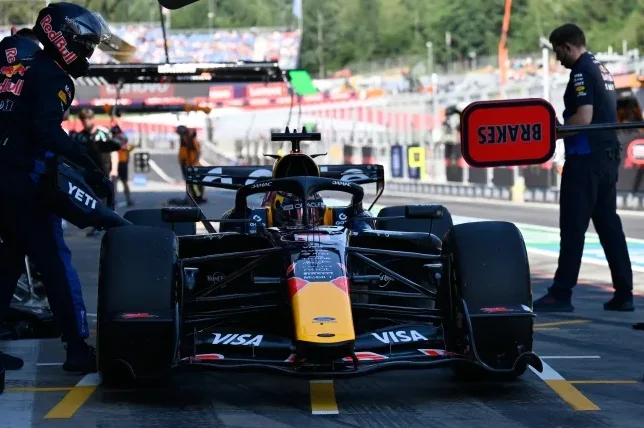 Vozač Red Bull Racinga u bolidu Formule 1 na pit stopu, sa mehaničarima koji obavljaju radove.