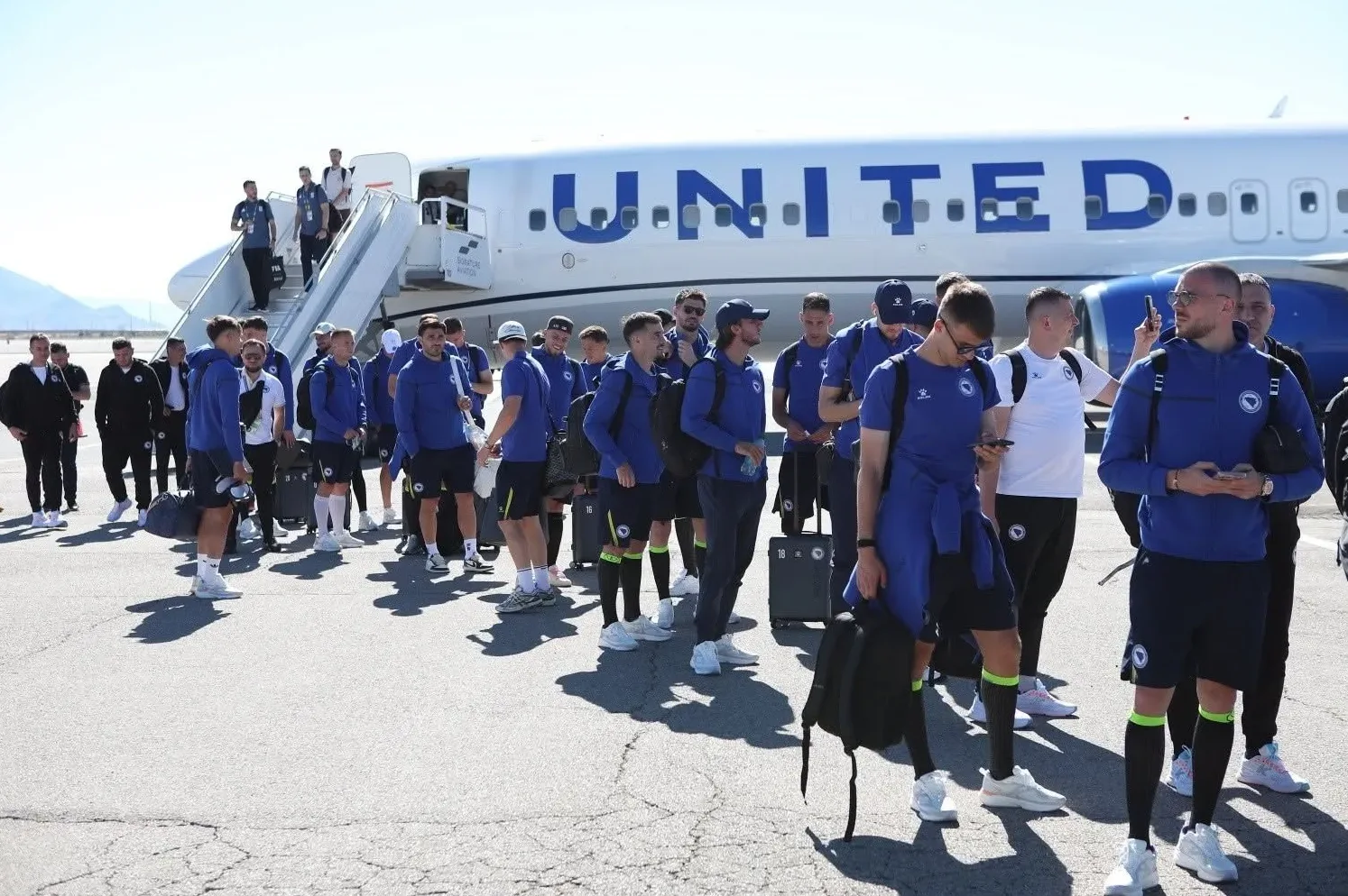 Fudbalska reprezentacija Bosne i Hercegovine u plavim dresovima iskrcava se sa aviona United Airlines na aerodromu.