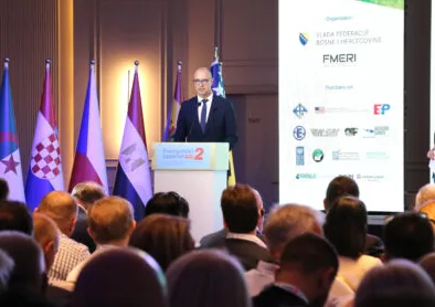Muškarac u tamnom odijelu i plavoj kravati stoji iza podijuma sa natpisom "Energetska budućnost 2" i drži govor pred publikom.