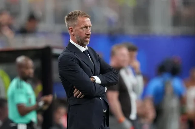 Menadžer Graham Potter u tamnom odijelu sa prekrštenim rukama na stadionu.