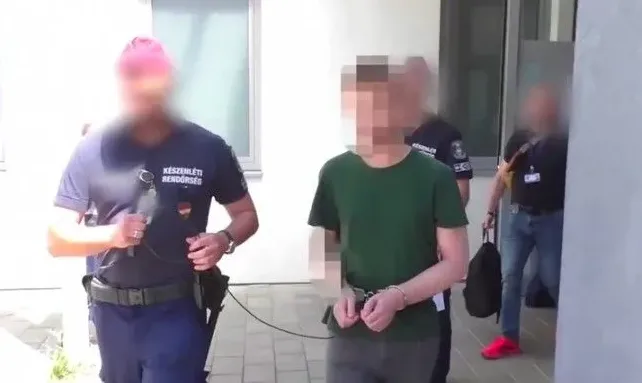 Policijski službenici u civilu i uniformi vode osobu s lisicama na rukama.