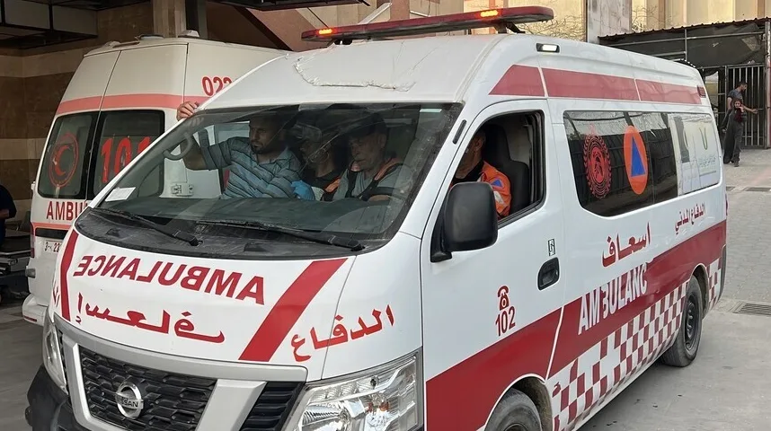 Ambulantna kola sa upaljenim rotacionim svjetlima ispred objekta, sa osobljem unutra i sa strane.