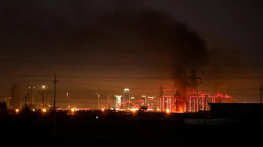 Industrijska zona osvijetljena noću, sa dimom i plamenom koji kuljaju iz postrojenja.