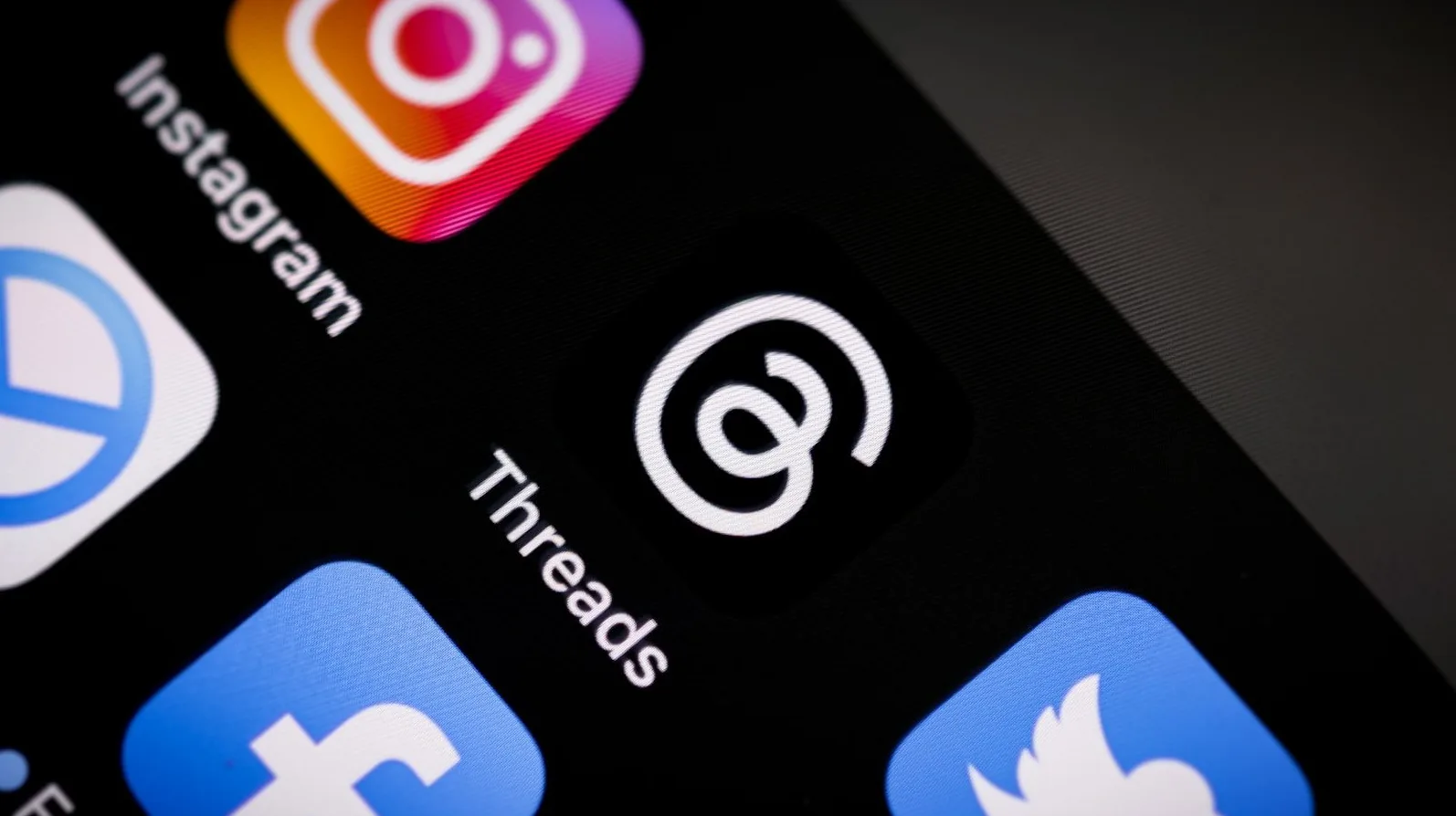 Ikona aplikacije Threads pored ikone Instagrama na crnom ekranu telefona.