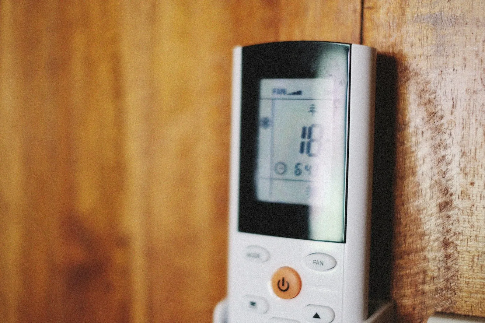 Daljinski upravljač klime sa upaljenim ekranom koji prikazuje temperaturu.