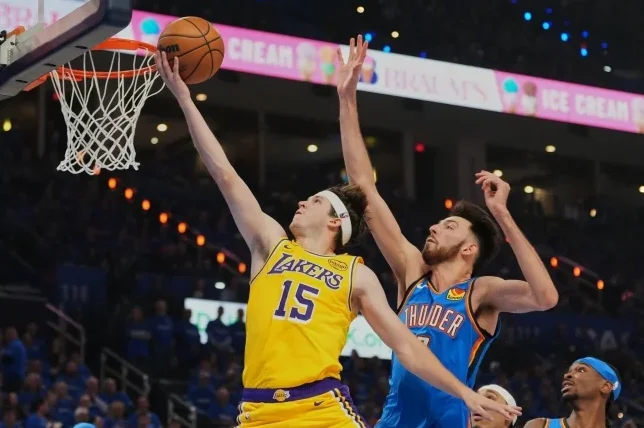 Košarkaš Los Angeles Lakersa, obučen u žuti dres s brojem 15, pokušava postići koš zakucavanjem, dok ga brani igrač Oklahoma City Thunder-a u plavom dresu s brojem 7.