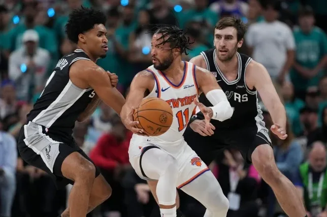 Košarkaš New York Knicksa, Džejlen Branson, sa loptom u rukama, dribla dok ga čuvaju igrači San Antonio Spursa.