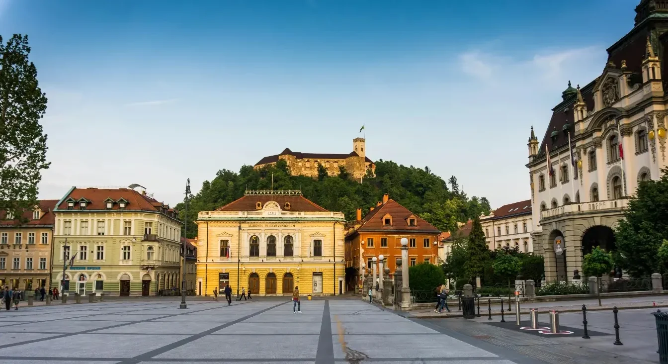 Pogled na Prešernov trg u Ljubljani sa Ljubljanjskim gradom u pozadini.