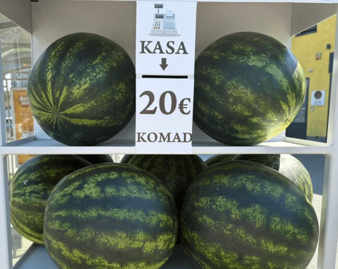 Velike zelene lubenice izložene na polici s natpisom 'KASA' i cijenom od 20 eura po komadu.