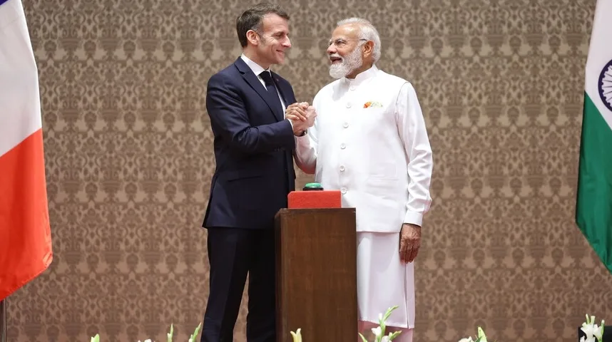 Emmanuel Macron i Narendra Modi se rukuju ispred zastava Francuske i Indije