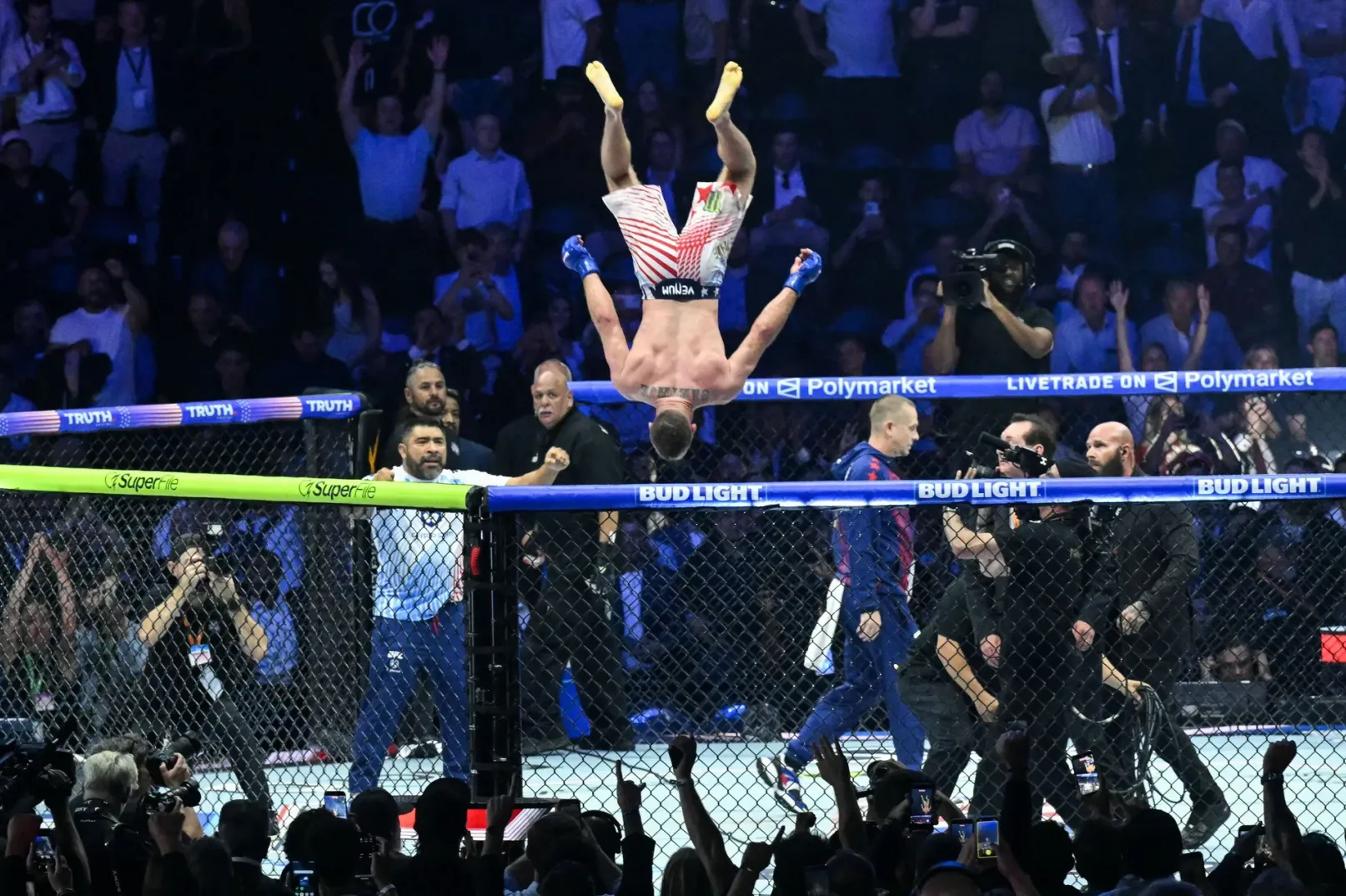 MMA borac visi naglavačke u zraku nakon što je izbačen iz ringa, tokom borbe, dok publika gleda.