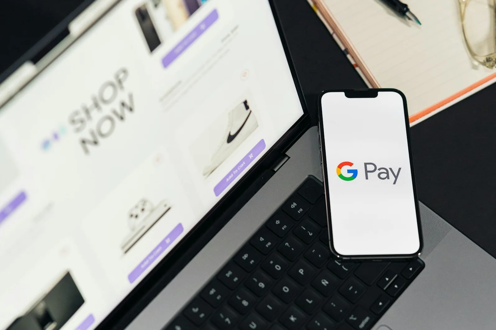 Mobilni telefon sa Google Pay aplikacijom na tastaturi laptopa, koji prikazuje online prodavnicu.