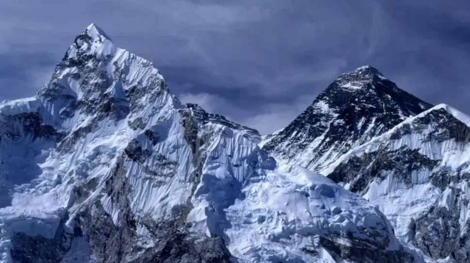 Pogled na snijegom prekriveni vrh planine Everest pod tamnim, oblačnim nebom.