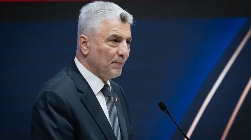 Muškarac srednjih godina sa sijedom kosom u tamnom odijelu i bijeloj košulji, govori na mikrofon.