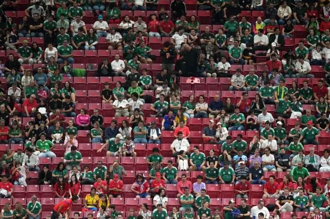 Veliki broj navijača sjedi na crvenim tribinama stadiona, noseći zelene i bijele majice, navijajući za svoj tim.