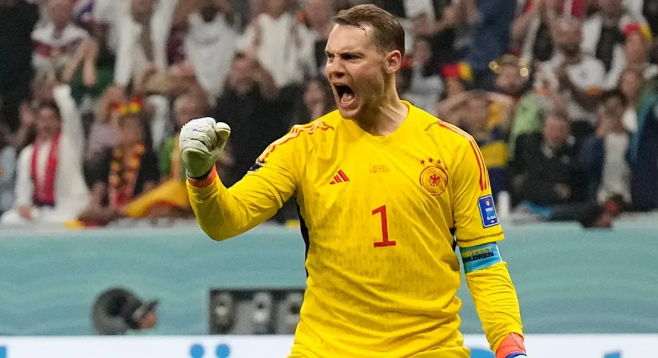 Golman njemačke nogometne reprezentacije u žutom dresu sa brojem 1, podignute pesnice i otvorenih usta u proslavi, na stadionu sa publikom u pozadini.