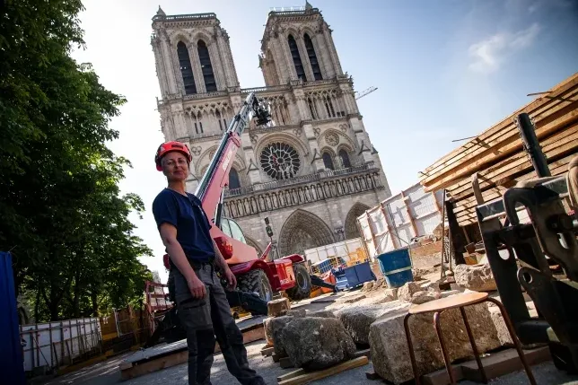 Žena radnica u zaštitnoj kacigi ispred katedrale Notre Dame u Parizu tokom radova obnove.
