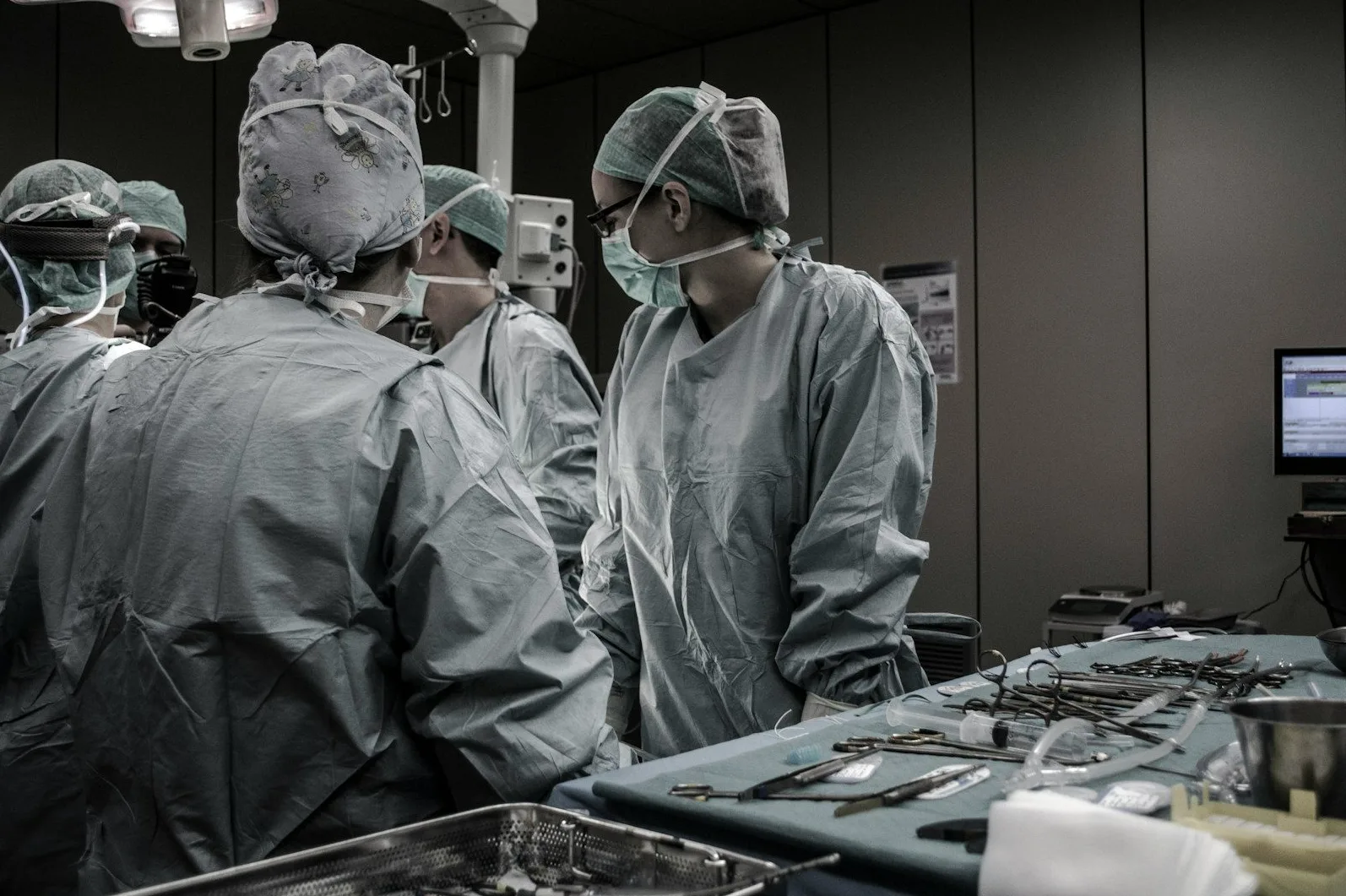 Grupa hirurga u sterilnoj opremi u operacionoj sali razgovara prije početka procedure.