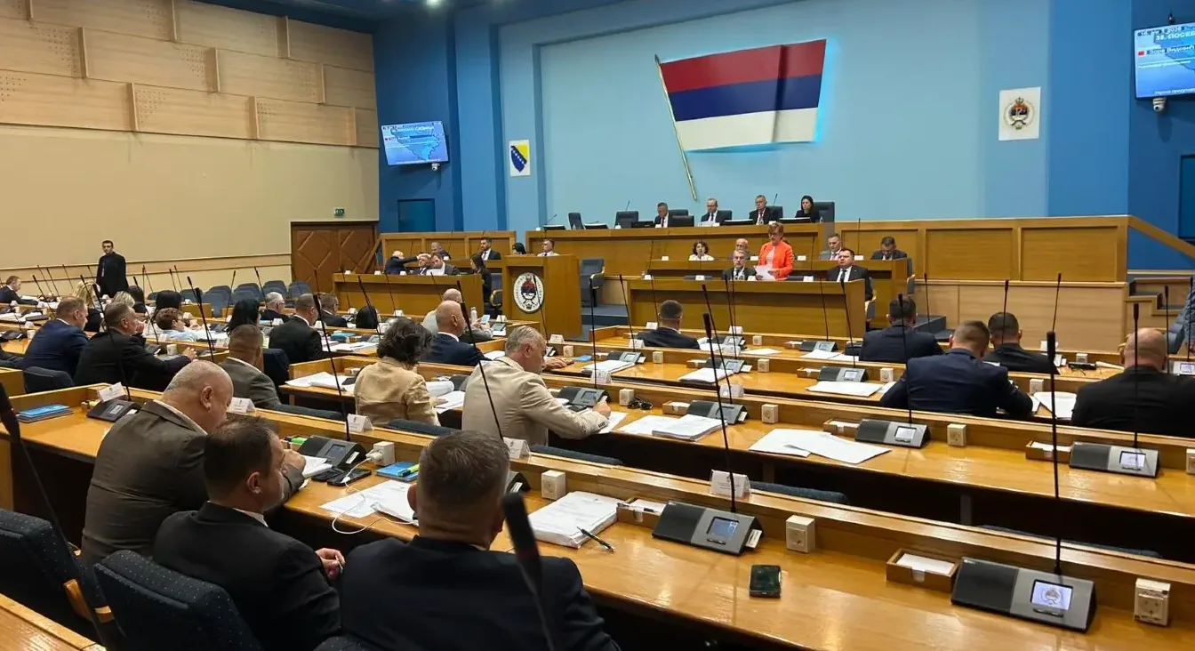Puna sala parlamenta s mnogo poslanika koji sjede za stolovima, zastava Republike Srpske se vidi na zidu.