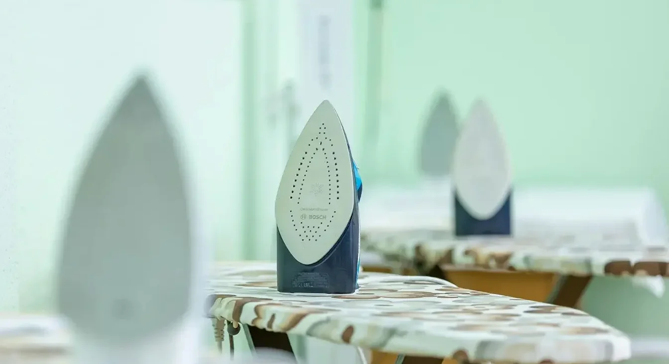 Detalj potplata Bosch pegle na daskama za peglanje sa zamagljenom pozadinom
