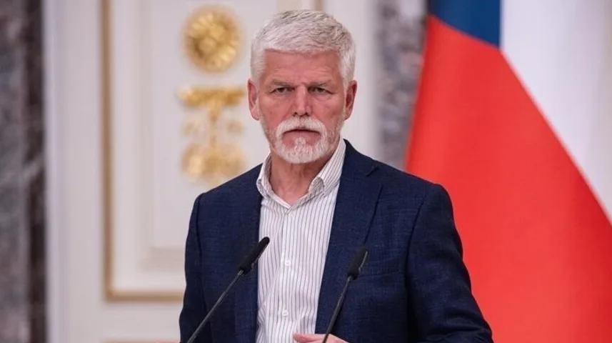Predsjednik Češke Petr Pavel govori sa dva mikrofona ispred zastave Češke Republike.