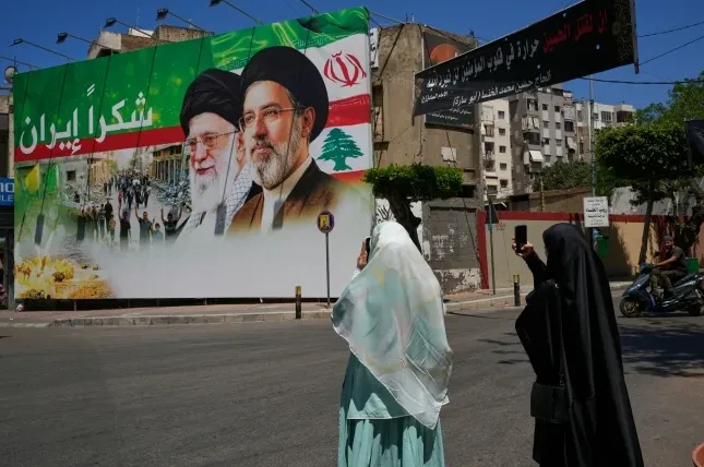 Ljudi slikaju mural na kojem su prikazana dvojica vjerskih vođa Irana i Libana, uz natpis na arapskom 'Hvala Iran'.