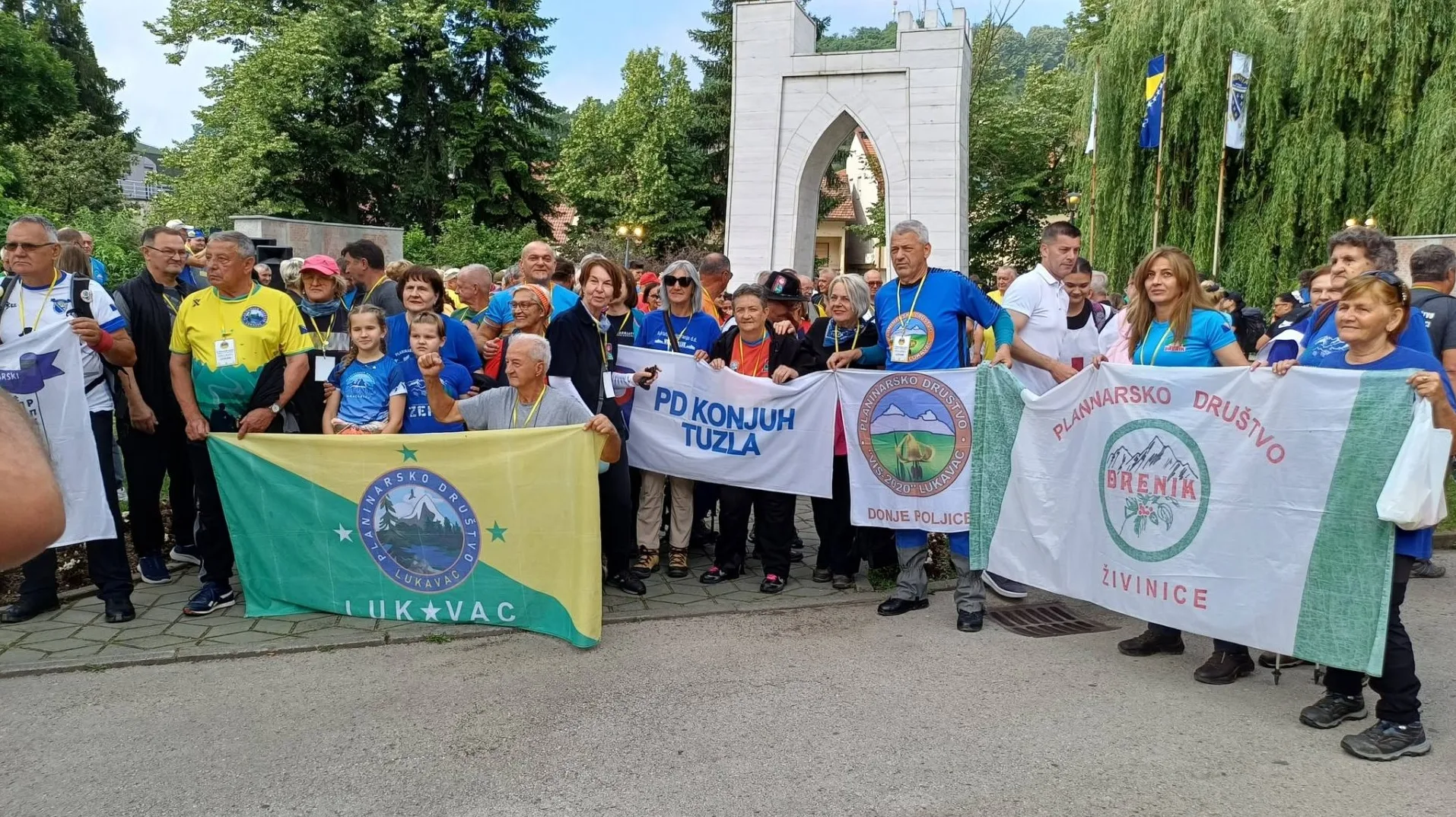 Grupa planinara drži zastave Planinarskog društva Konjuh Tuzla, Planinarskog društva Lukavac i Planinarskog društva Brenik Živinice.