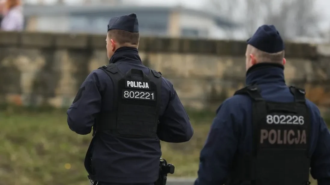 Dva policajca u tamnim uniformama sa prslucima na kojima piše 'POLICIJA' i brojevima