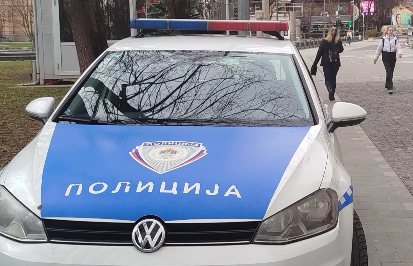 Policijsko vozilo sa plavim i crvenim rotacionim svjetlima i natpisom "POLICIJA" na haubi.