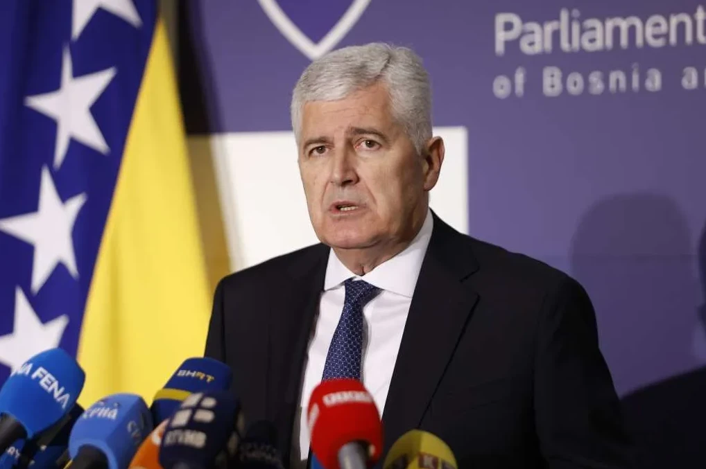 Političar sa sijedom kosom u tamnom odijelu i plavoj kravati drži govor ispred zastave Bosne i Hercegovine i natpisa "Parliament of Bosnia and Herzegovina".
