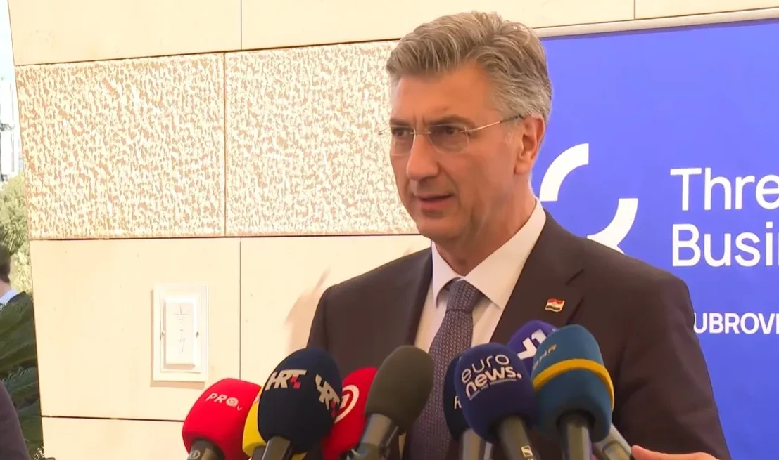 Političar u tamnom odijelu i sa naočalama govori u mikrofone novinara. Na reveru odijela mu je zastavica Republike Hrvatske.