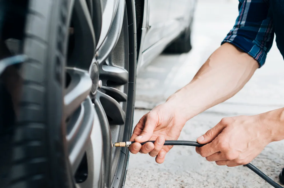Čovjek pumpa gumu automobila