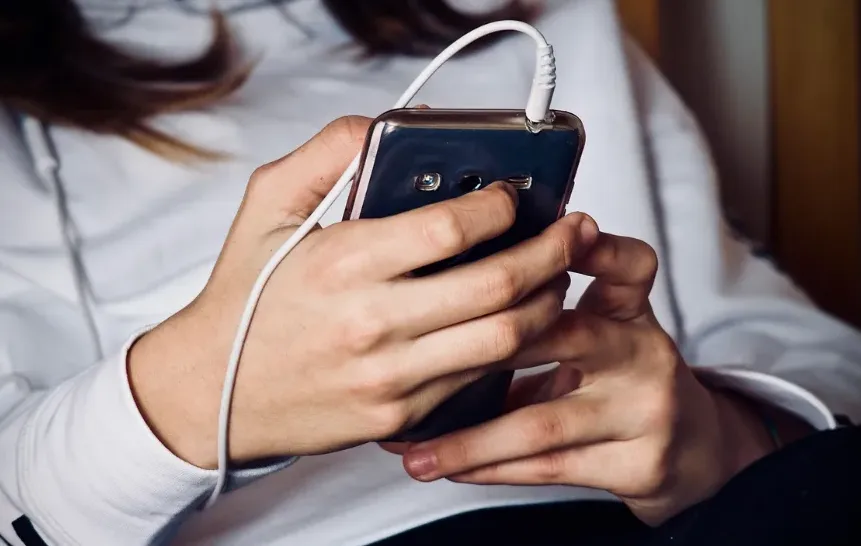 Mlada osoba koristi pametni telefon sa priključenim slušalicama.