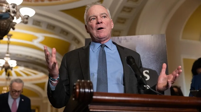 Senator Tim Kaine drži govor ispred mikrofona, gestikulirajući rukama.