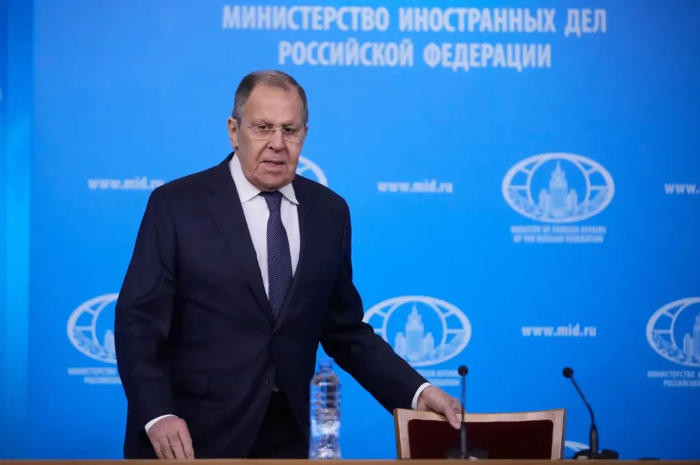 Sergej Lavrov, ministar vanjskih poslova Ruske Federacije, u tamnom odijelu i sa bijelom košuljom i plavom kravatom, stoji ispred plave pozadine sa logom ministarstva.